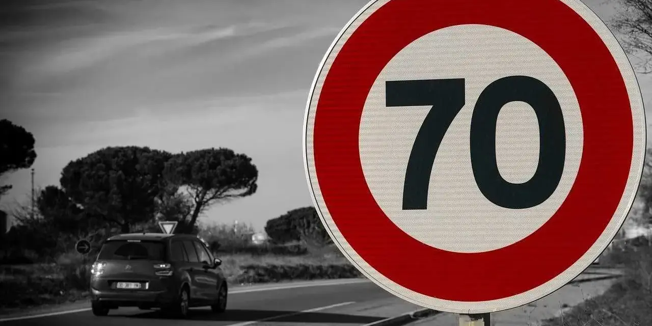 Znak ograniczenia prędkości 70 km/h. Samochód jedzie po drodze, gdzie dopuszczalna prędkość na autostradzie jest ograniczona.
