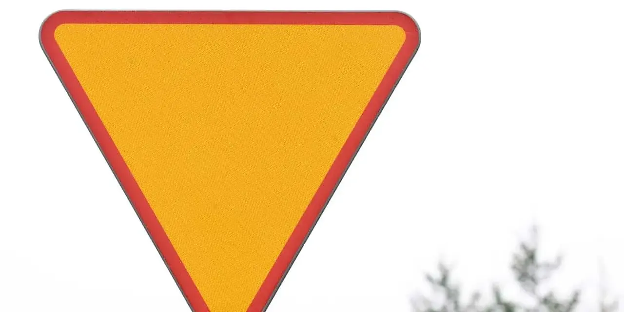 Żółty trójkąt z czerwoną obwódką, znak a7, ostrzega przed zbliżaniem się do skrzyżowania.